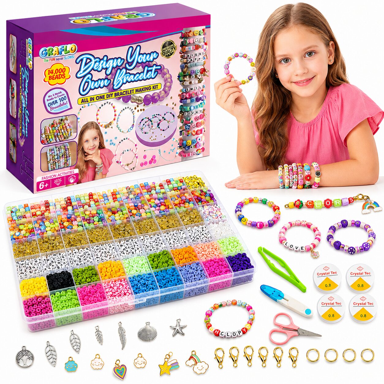 A girl holding a finished beaded bracelet beside the GRAFLO Design Your Own Bracelet box, with the 14,000 bead tray, charms, clasps, jump rings, elastic cords, scissors and tweezers laid out