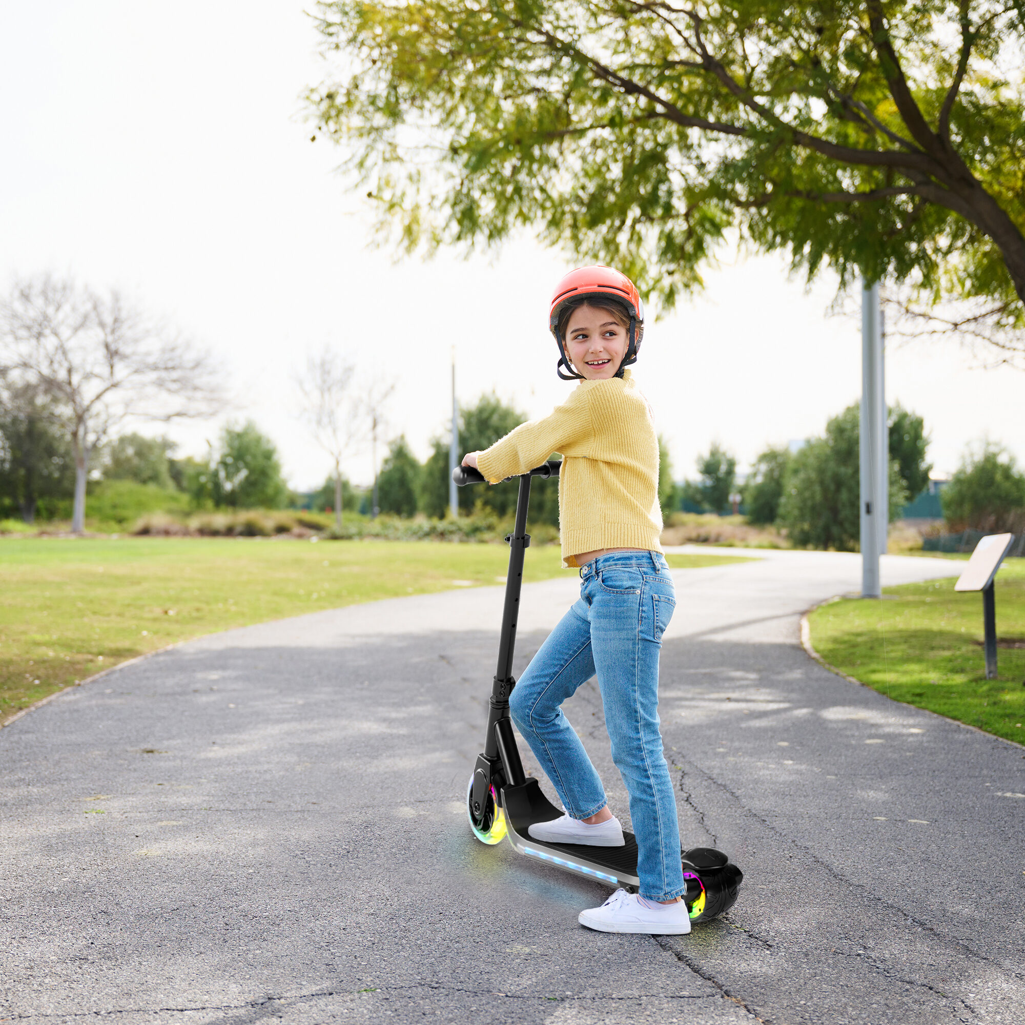 A girl riding the GRAFLO electric scooter along a park path