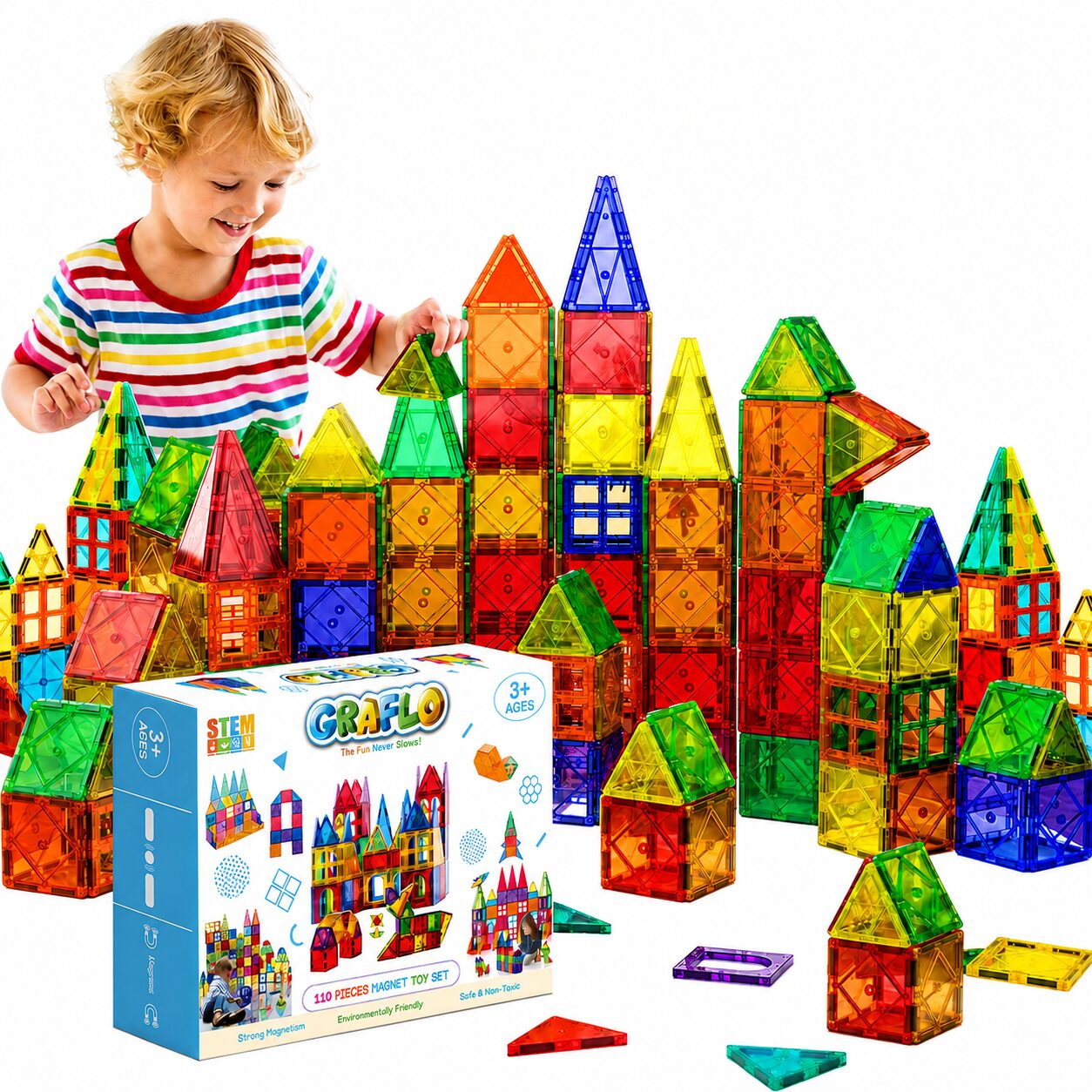 A child building a tall castle from the GRAFLO 110-piece magnetic tiles set, shown with the retail box and loose coloured tiles
