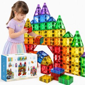 A girl building a tall magnetic tile castle beside the GRAFLO 70 pieces magnet toy set box, with stacks of coloured tiles in front