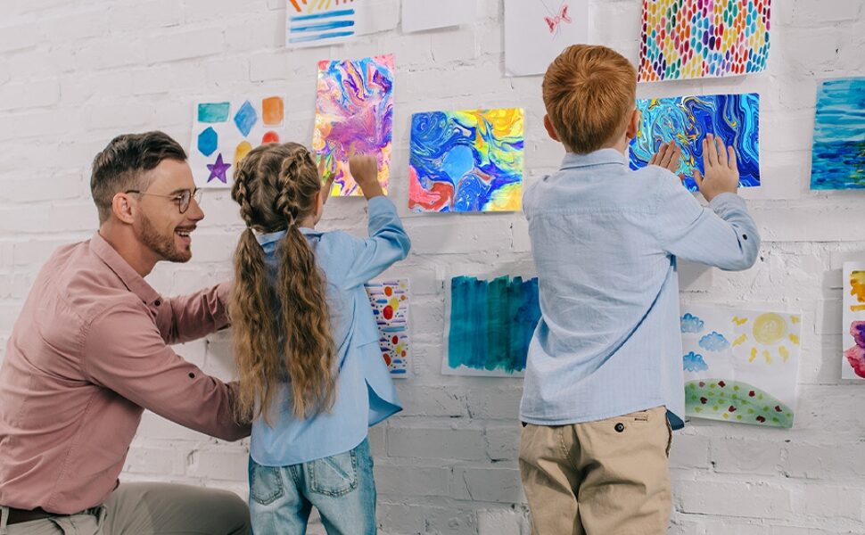 A father and two children pinning finished marbled prints to a wall