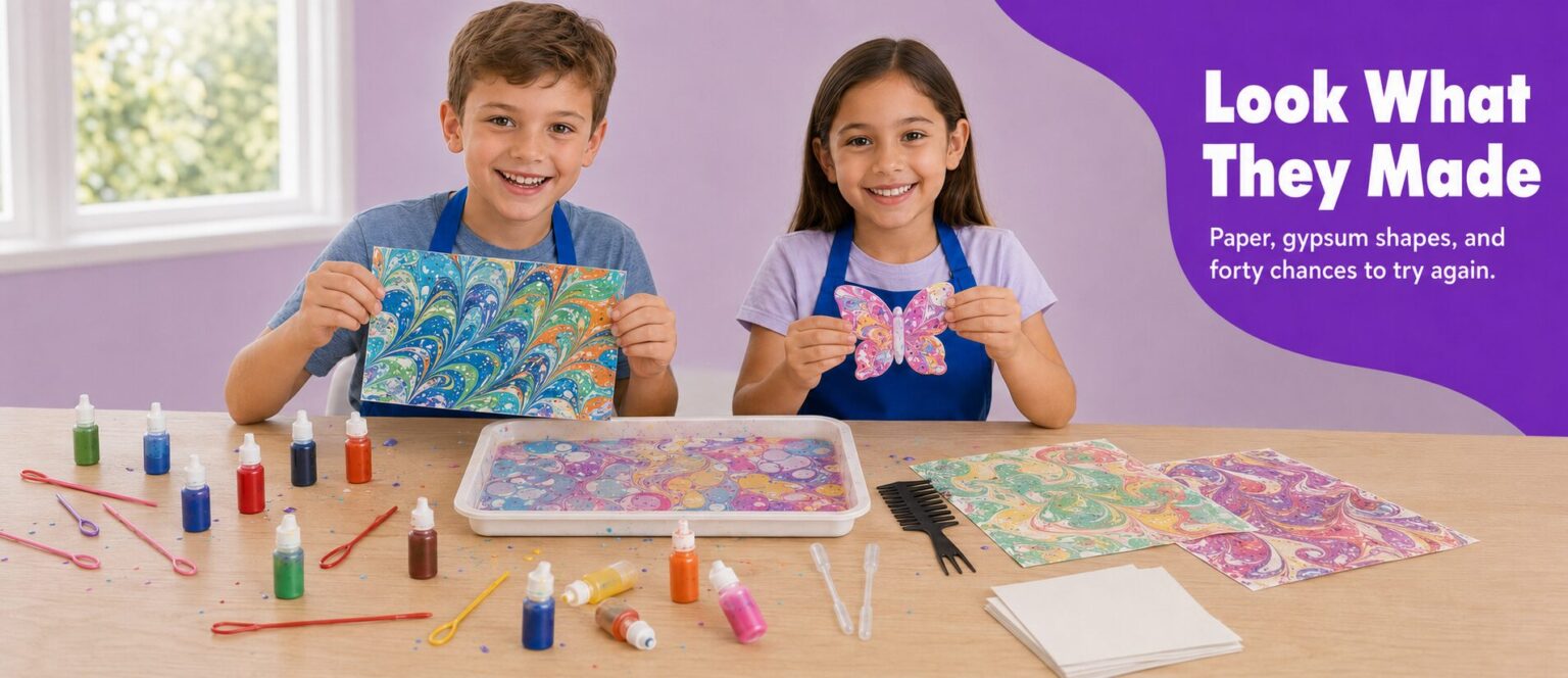 Two children holding up finished marbled prints and a marbled gypsum butterfly
