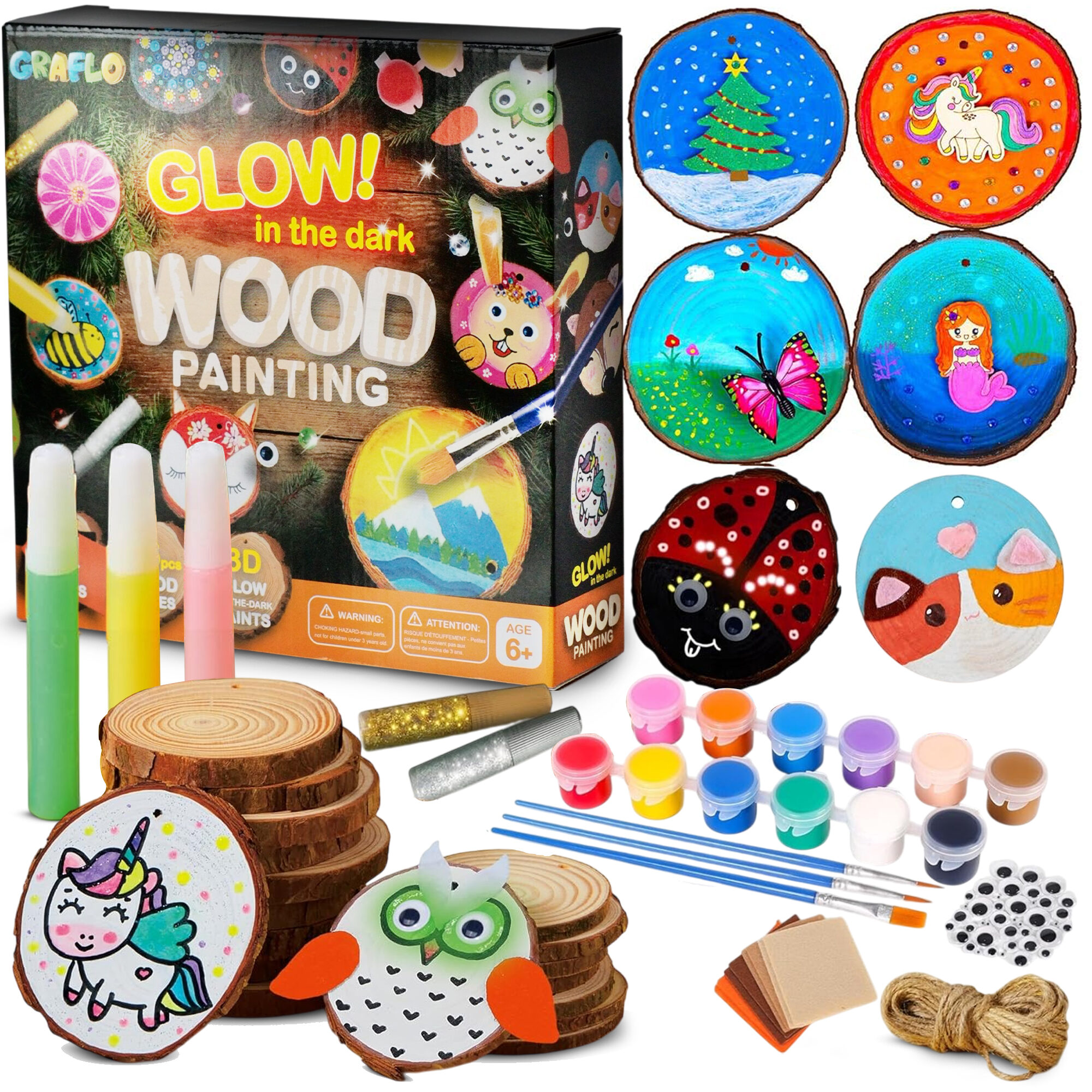 GRAFLO glow in the dark wood painting kit box with painted wood slices showing a Christmas tree, a unicorn, a butterfly, a mermaid, a ladybird and a cat, plus blank wood slices, glitter glue, twelve paint pots, brushes, wiggly eyes, felt sheets and jute twine